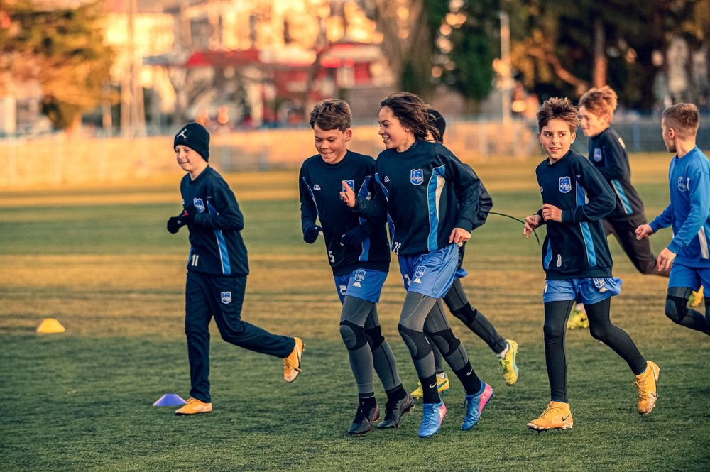 Entrenamiento de fútbol base con varios jugadores trabajando en el campo
