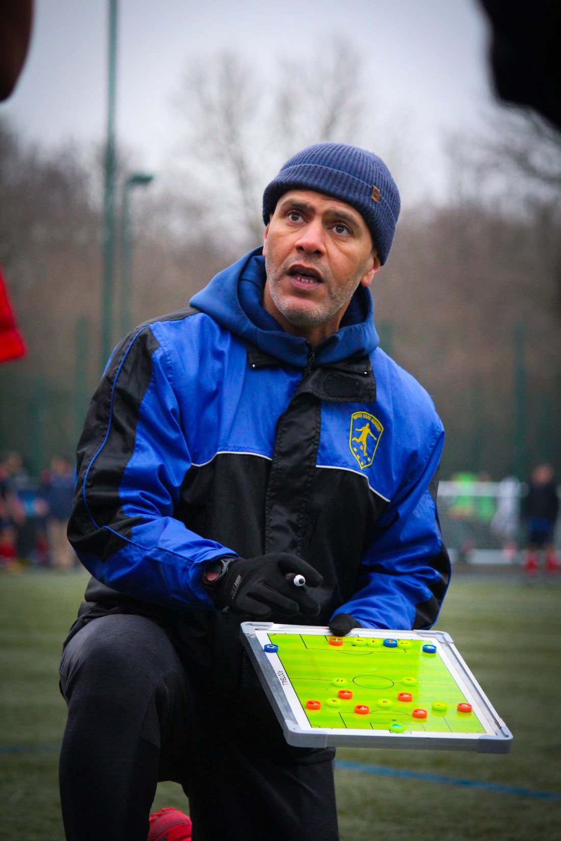 Entrenador con una pizarra táctica preparando la sesión a pie de campo